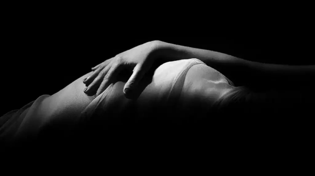 Corpo in chiaro scuro dove è poggiata una mano femminile | Corpo e anima