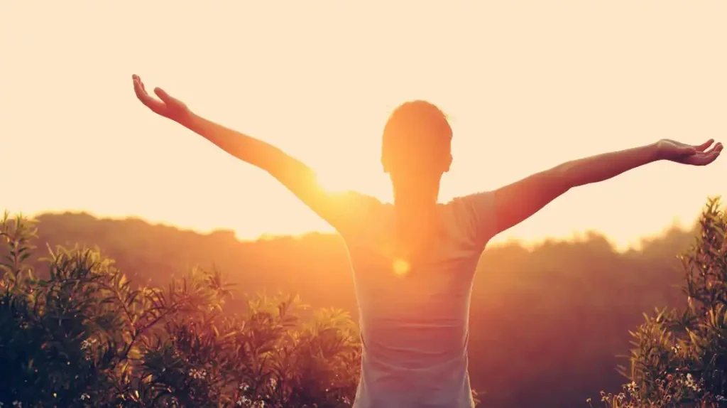 rilascio emozionale: persona di spalle immersa nella luce che apre le braccia al cielo | Corpo e anima
